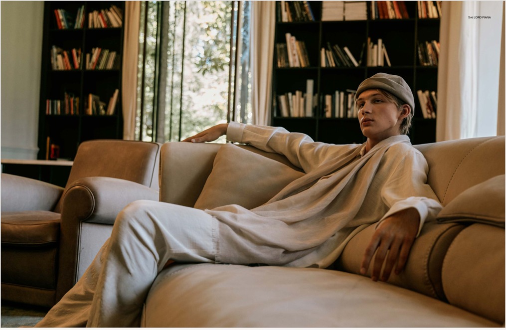 Spread — Hermès reclined on a beige sofa with bookshelves.