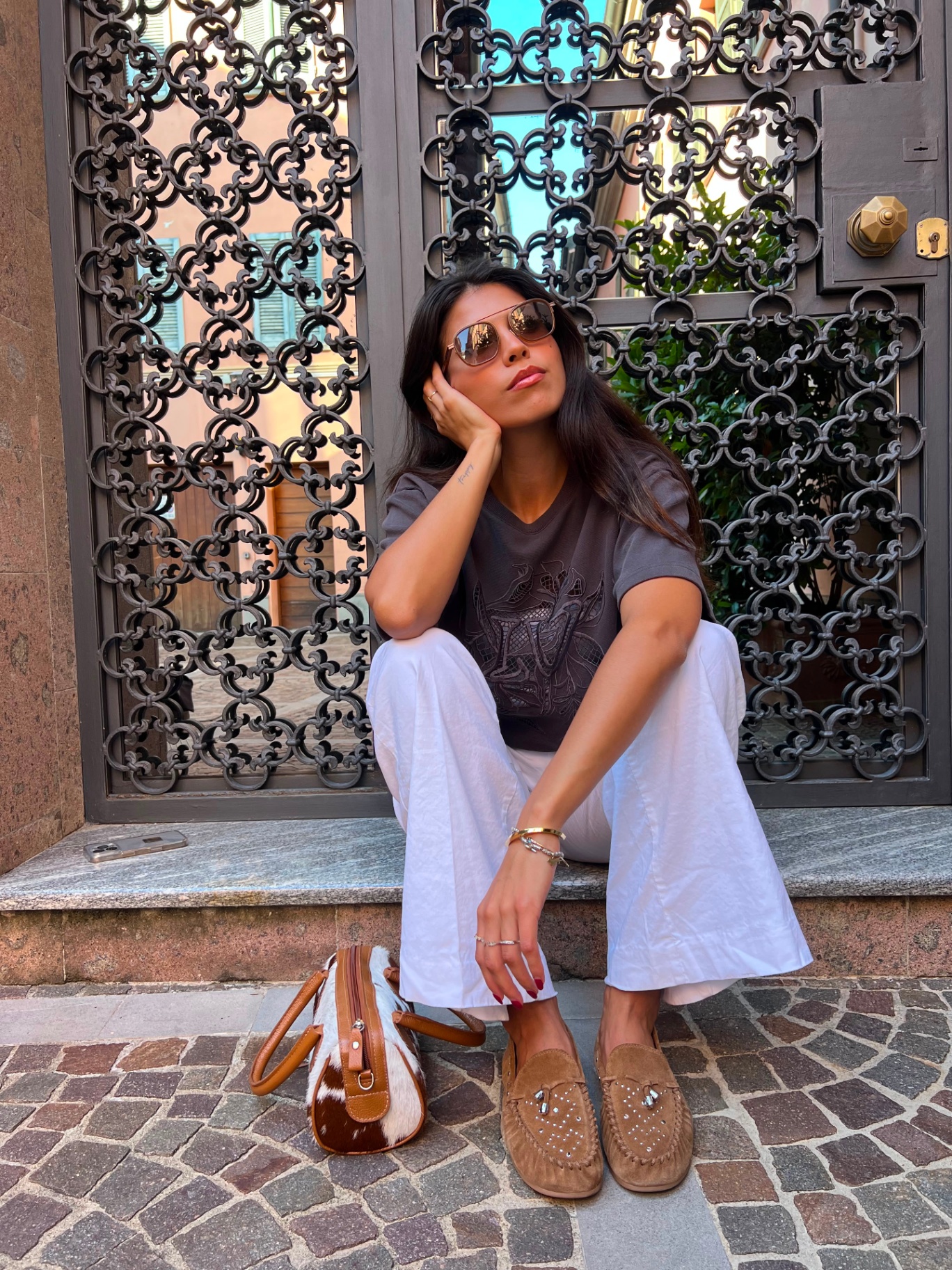 Personal styling — sunglasses, seated portrait by iron gate